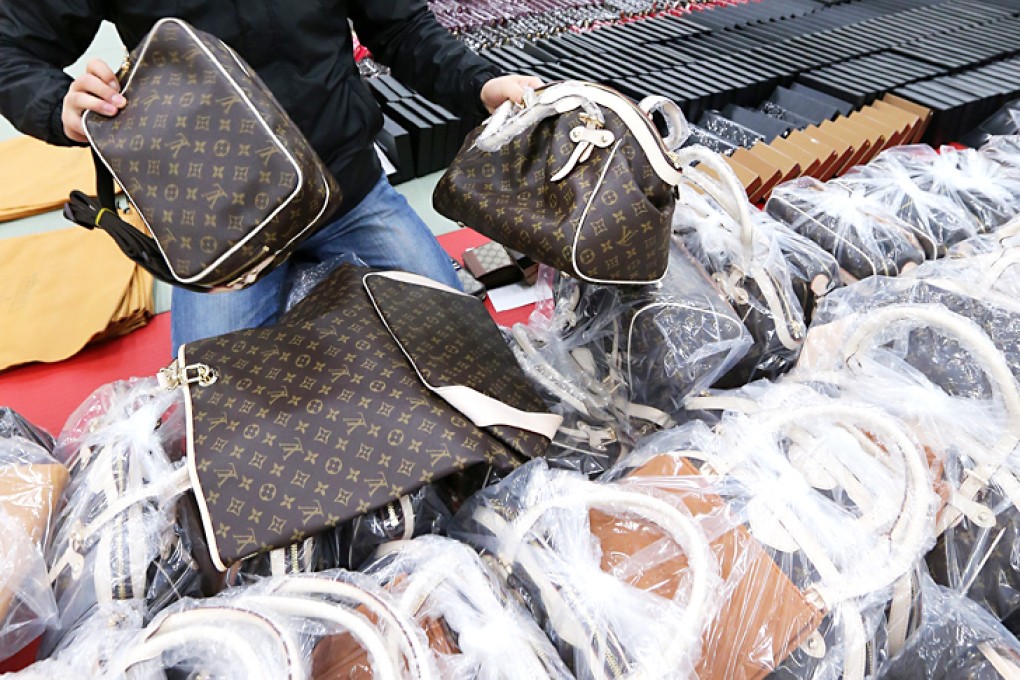 An international crime investigator sorts out counterfeit foreign-brand bags and purses confiscated from two makers of the fake goods. Photo: EPA