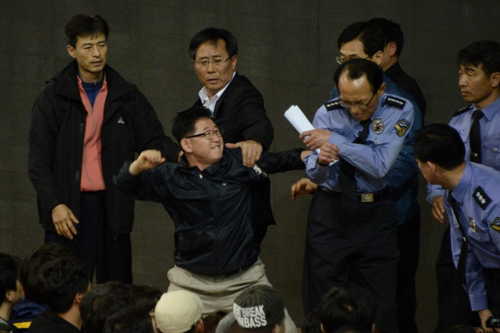 A relative takes aim at a policeman during a briefing on the ongoing rescue and recovery operation. Photo: AFP