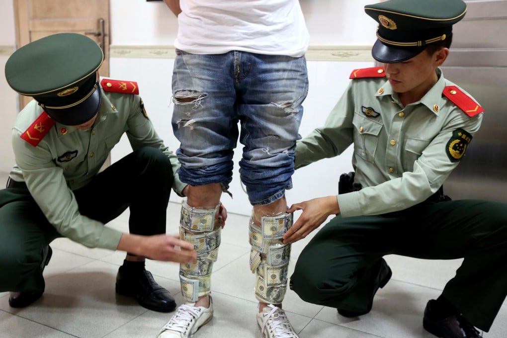 Two armed policemen check a Hong Kong man's legs wrapped with US dollars notes. Photo: Imaginechina