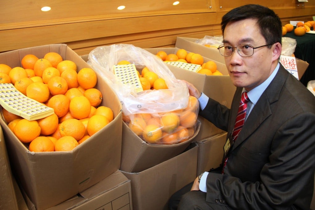 Customs' intellectual property officer Lam Yau-tak shows off some of the haul of fake Sunkist oranges. Photo: SCMP Pictures