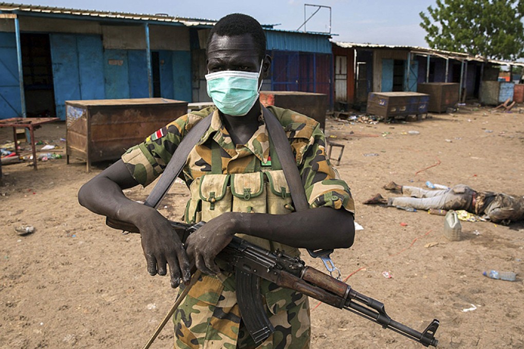 A rebel fighter wears a mask near a body in front of a mosque where people were massacred at in Bentiu, South Sudan. Photo: Reuters