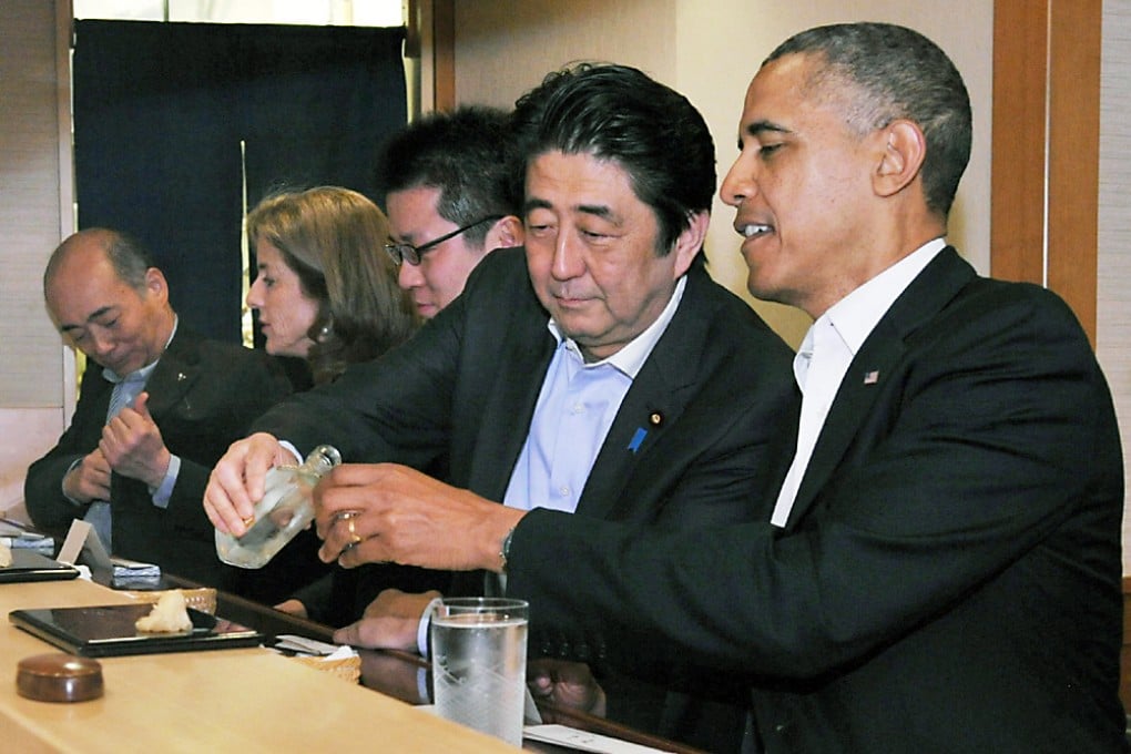 Shinzo Abe pours a drink for Barack Obama in the Sukiyabashi Jiro restaurant. Photo: AFP