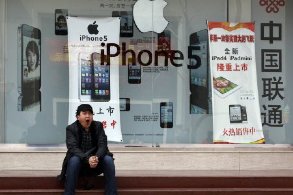 A man yawns in front of a mobile phone shop bearing an advertisement of Apple's iPhone in Beijing. Photo: Reuters