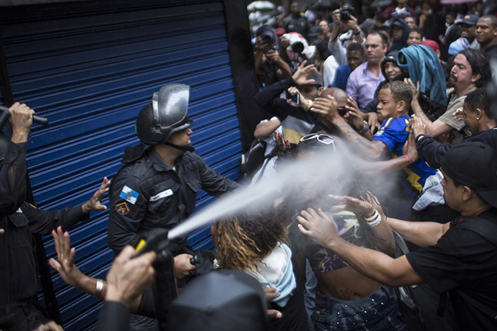A woman is pepper sprayed as residents of the Pavao-Pavaozinho slum clash with riot police during a protest in Rio de Janeiro on Thursday. Photo: AP