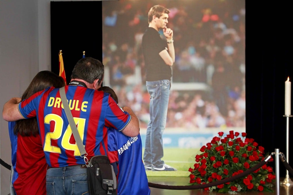 A family hugs each other in front of a picture of former Barcelona coach Francesc 'Tito' Vilanova at the Camp Nou. Photo: EPA