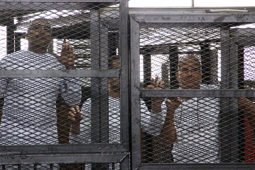 Al-Jazeera English bureau chief Mohammed Fahmy (from left), producer Baher Mohamed and correspondent Peter Greste appear in a defendant's cage in a courtroom along with several other defendants during their trial on terror charges in Cairo. Photo: AP