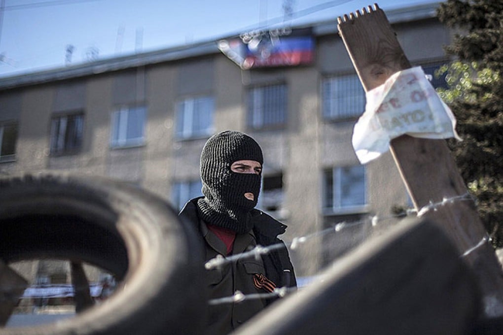 A pro-Russian masked supporter stands behind a barricade at a government building in Horlivka. Photo: EPA