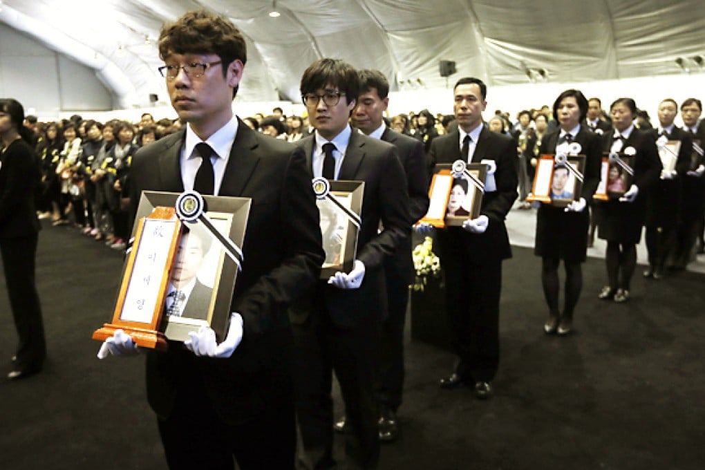 Funeral service employees carry portrait of victims of the sunken ferry Sewol at the official memorial altar in Ansan. A probe into the disaster has heard that warnings over the ship’s seaworthiness were ignored. Photo: Reuters