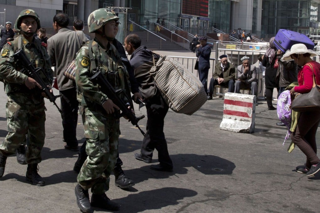 Heavily armed Chinese paramilitary policemen march past the Urumqi South Railway Station in Xinjiang. Photo: AP