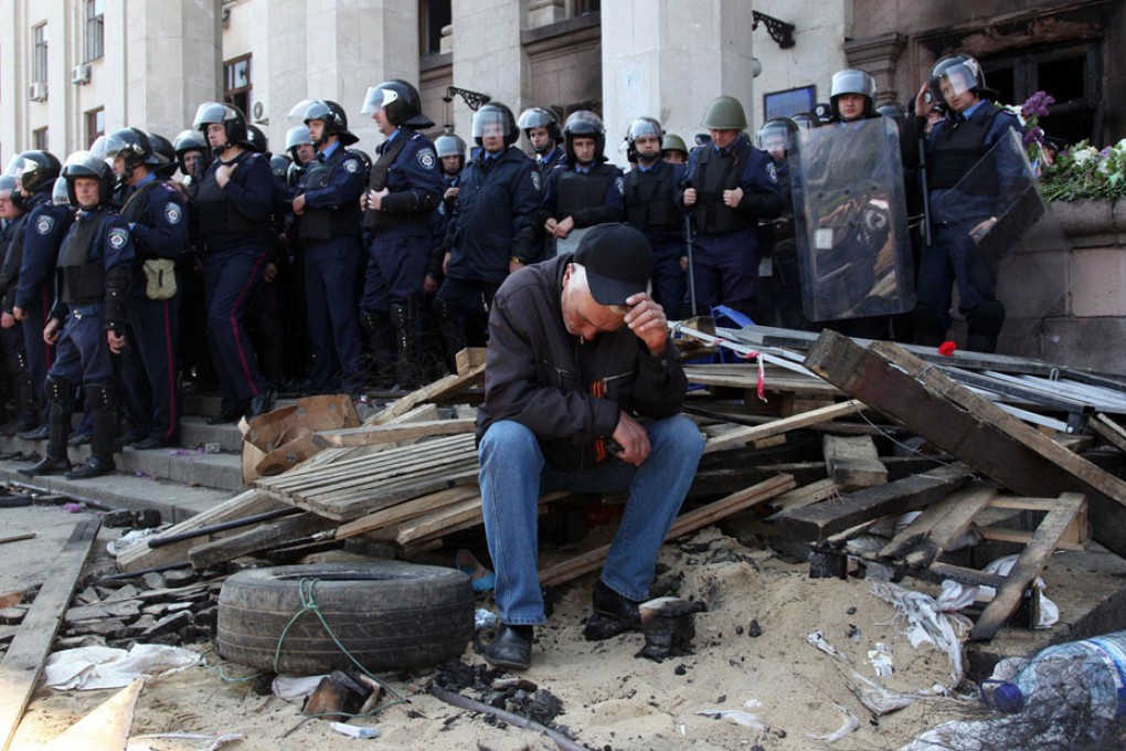 A Pro-Russian activist sits in front of policemen guarding the burned trade union building in Odessa where dozens were killed after deadly street clashes earlier. Photo: AFP