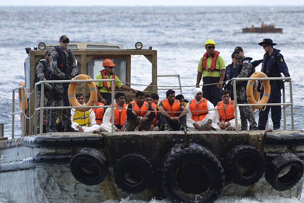 Australian customs officials and navy personnel escort rescued asylum-seekers onto Christmas Island in this image from September 2013. Photo: Reuters