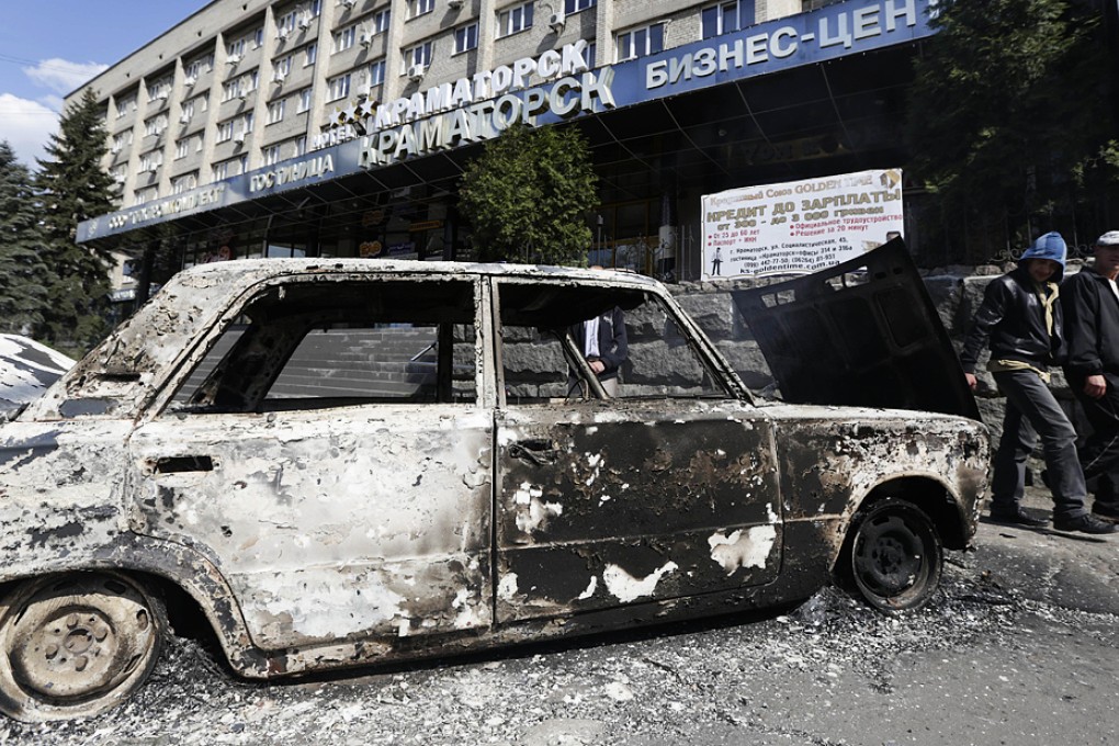 Two men walk past a burnt car in Kramatorsk. Photo: AFP