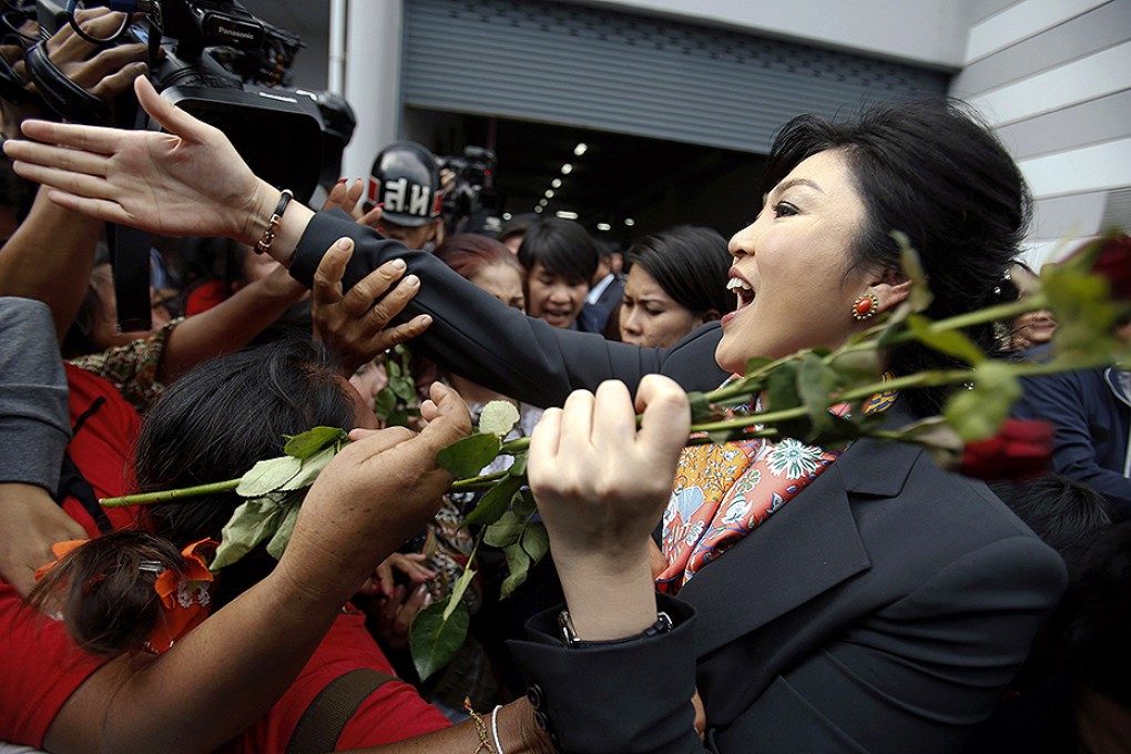 Thailand's Prime Minister Yingluck Shinawatra greets her supporters as she leaves the Permanent Secretary of Defence office in Bangkok. Photo: Reuters