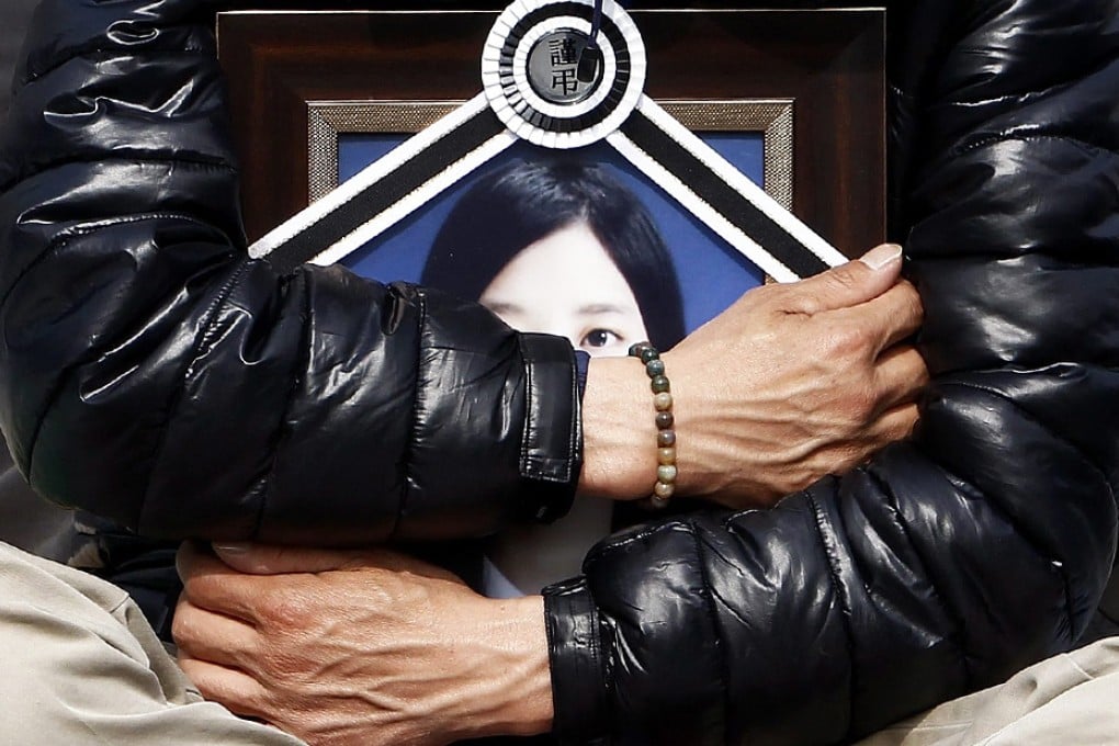 A bereaved father of one the victims of the South Korean ferry
disaster last month holds a portrait of his deceased daughter as families sit on the ground near Seoul’s presidential house, demanding a meeting with President Park Geun-Hye. Photo: EPA