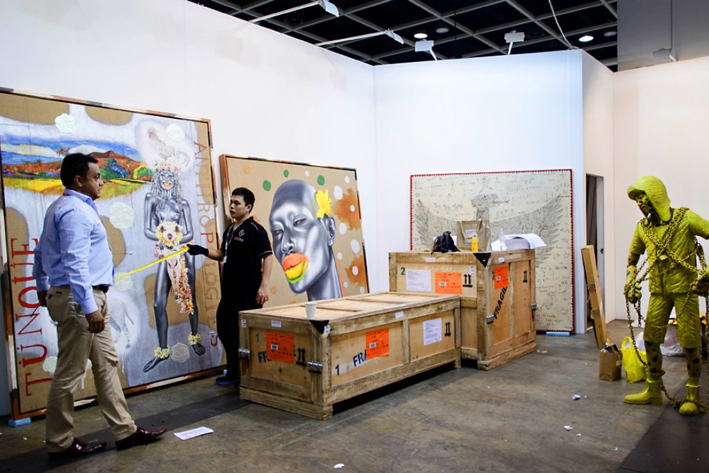An exhibitor (left) and a worker install artworks at a booth of the Art Basel venue in Hong Kong. Photo: AFP
