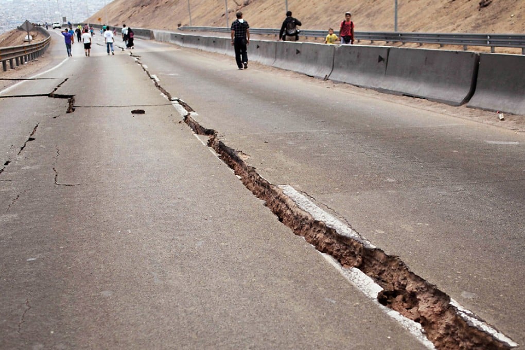 People walk along a road damaged by a powerful 8.2-magnitude earthquake that hit off Chile's Pacific coast, in Iquique, northern Chile in March 2014. Photo: AFP