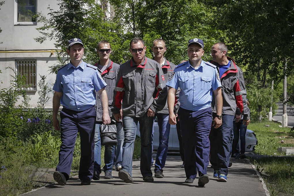 Workers of Metinvest, majority-owned by Rinat Akhmetov's System Capital Management, and police officers conduct a joint patrol in Mariupol on Friday. Photo: Reuters