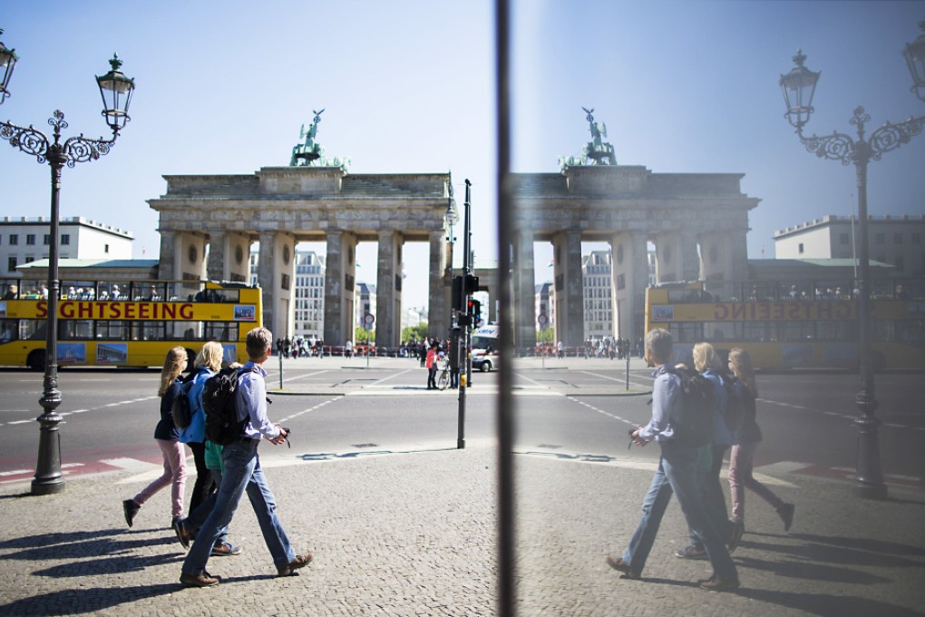 The Brandenburg Gate and tourists are mirrored in a information panel on a sunny day in Berlin, Germany. Photo: AP