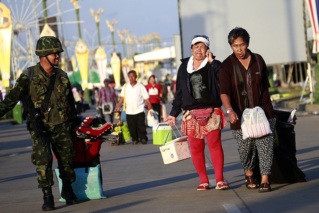 A Thai soldier carries helps pro-government demonstrators leaving their demonstration site. Photo: AP