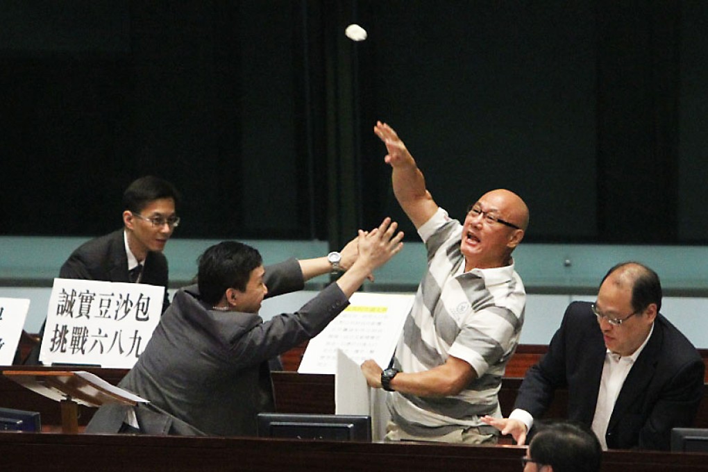 People Power's Albert Chan Wai-yip hurls a bun at the chief executive as security staff rush to restrain him. Photo: Felix Wong