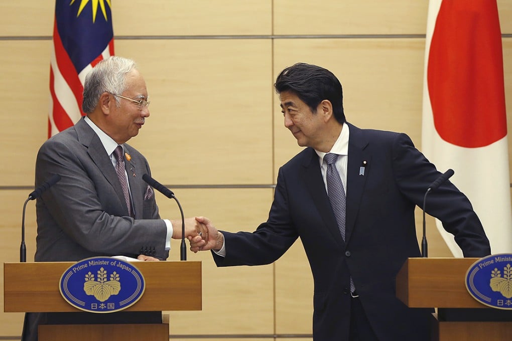 Najib Razak and  Shinzo Abe shake hands at the start of their talks at Abe's official residence in Tokyo. Photo:  EPA