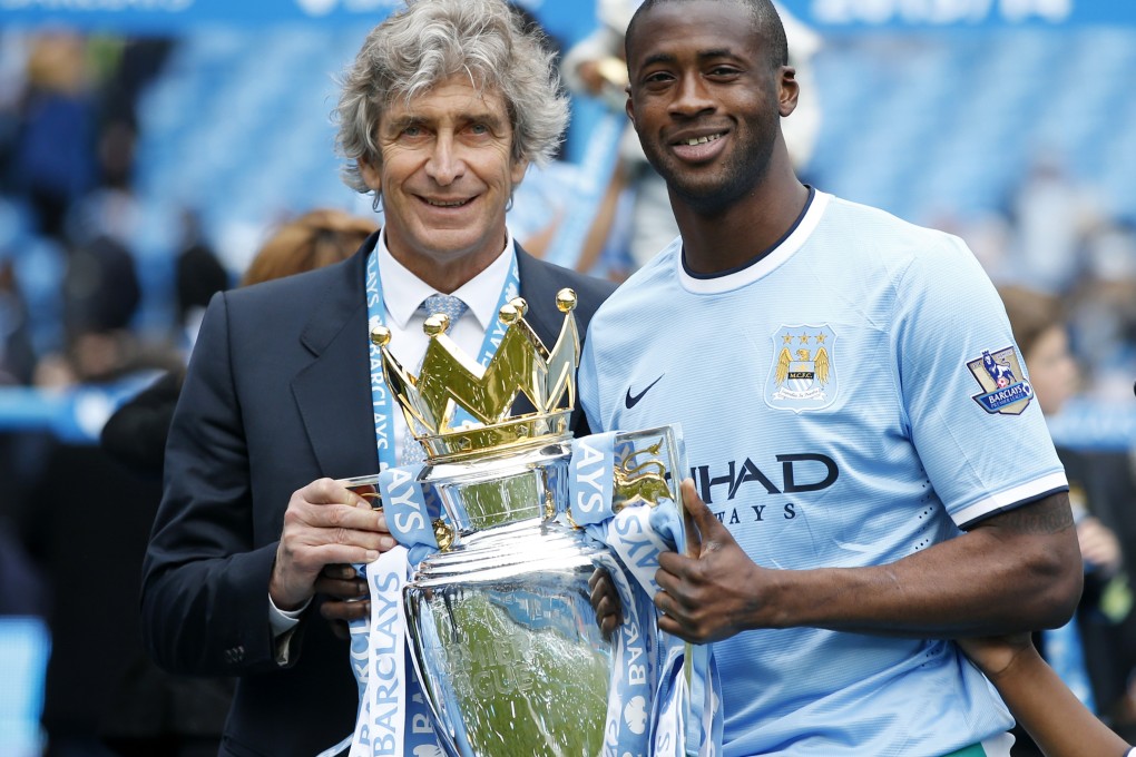 Yaya Toure (right) poses with Manchester City manager Manuel Pellegrini and the English Premier League trophy. Photo: Xinhua