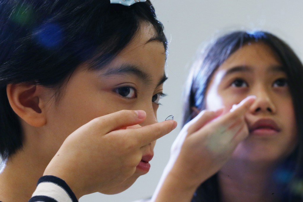 Two youngsters show the ortho-k lenses they wear every night to slow down myopia progression. Photo: SCMP