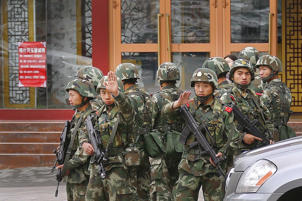 Paramilitary policemen gesture to stop a photographer from taking pictures as they stand guard after explosives attack hit downtown Urumqi on Thursday. Photo: Reuters