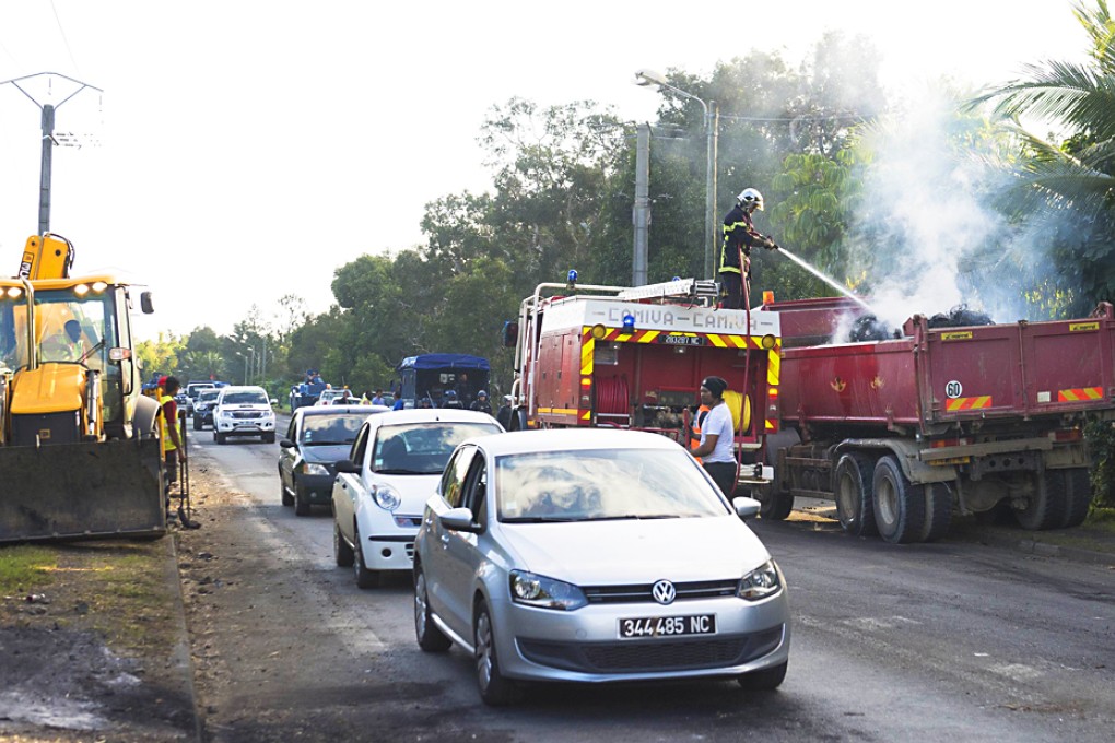 A French firefighter extinguishes burning debris that were used to create a roadblock on a road in Mont-Dore in New Caledonia. Photo: AFP