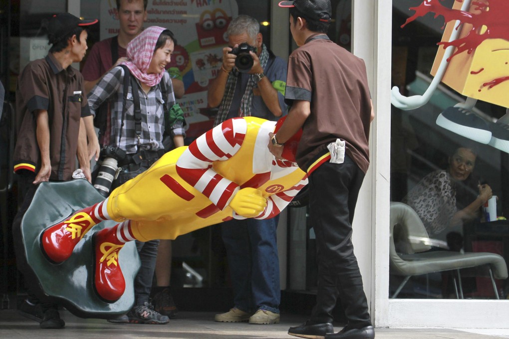 Workers remove a Ronald McDonald mannequin from outside a McDonald's restaurant in Bangkok after it was the scene of a small gathering of anti-coup protesters. Photo: AP