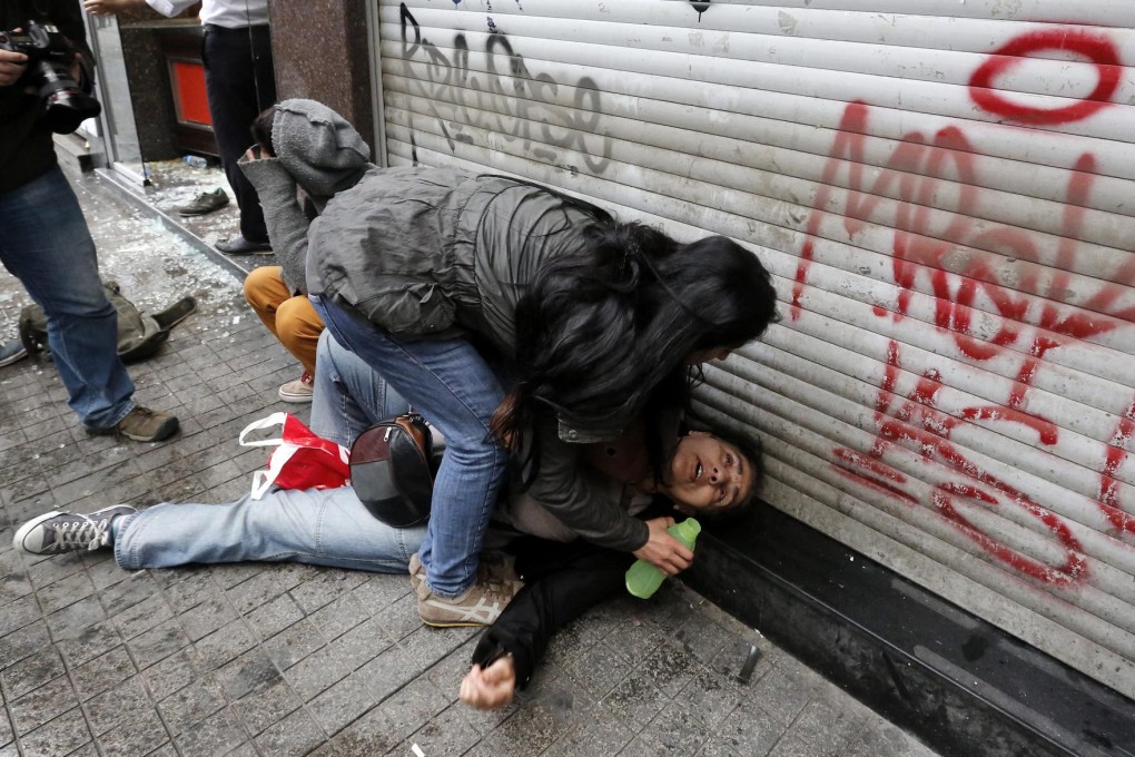 A woman helps a friend during a tear gas attack. Photo: EPA