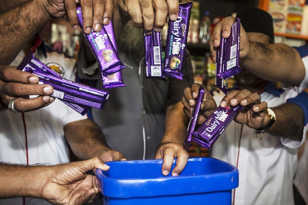 Malaysian Muslim Consumer Association members throw Cadbury Dairy Milk bars into a thrash bin during a protest against Cadbury products, at a press conference in Kuala Lumpur, Malaysia. Photo: EPA