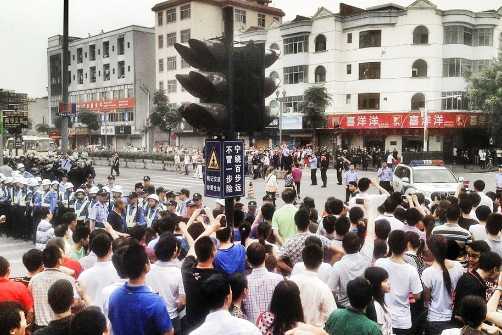 Workers protest during a strike as police stand guard at a crossroads near the factory area of Yue Yuen Industrial in Dongguan.