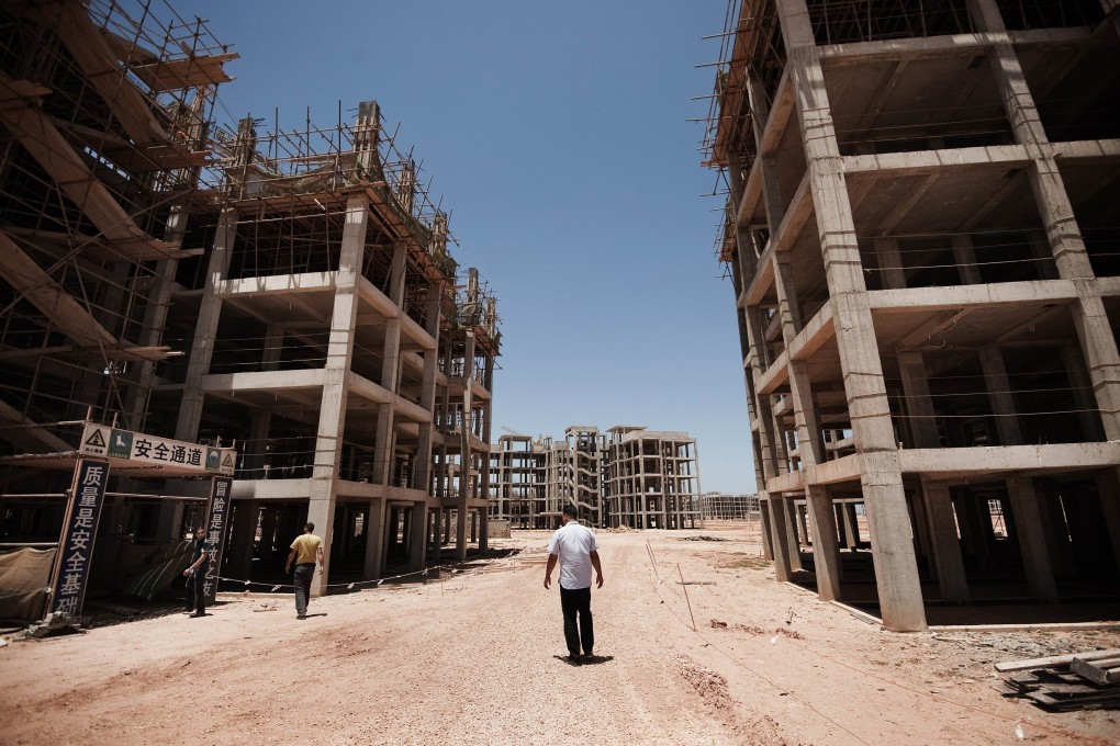 People walk past the abandoned construction site of the "New Benghazi" project. The 2011 civil war in Libya forced Chinese construction companies to abandon billions of dollars worth of equipment and business, and 30,000 Chinese workers were evacuated. Photo: AFP