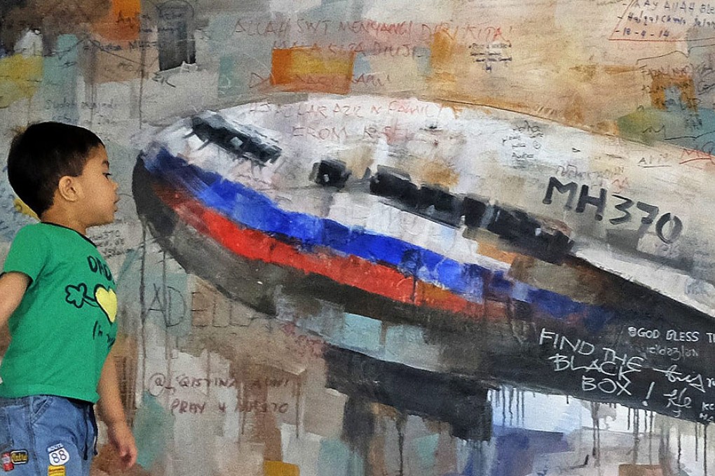 A boy looks at a painting of the missing Flight MH370 aircraft at the viewing gallery of the Kuala Lumpur International Airport. Photo: EPA