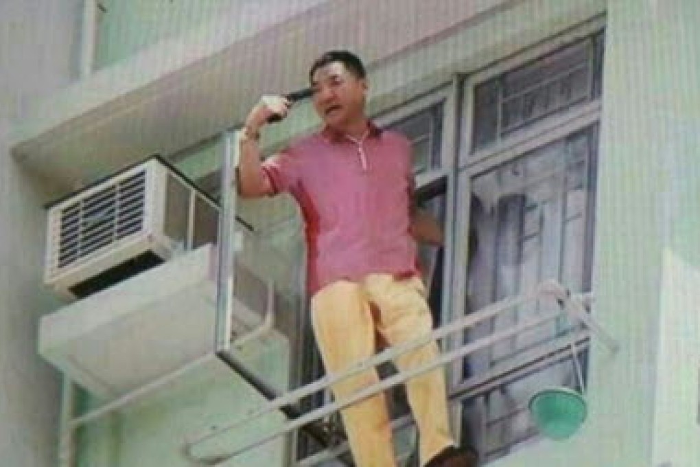 Lee Tak-yan points a gun at his head on the ledge of his flat.