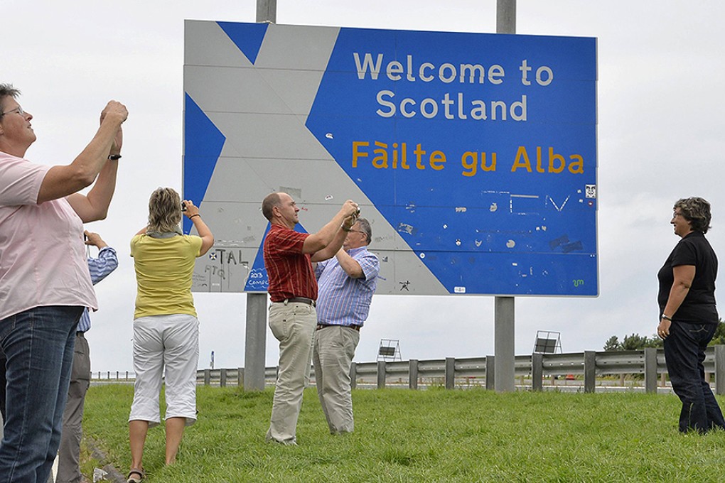 Tourists take photographs at the England-Scotland border. Photo: EPA