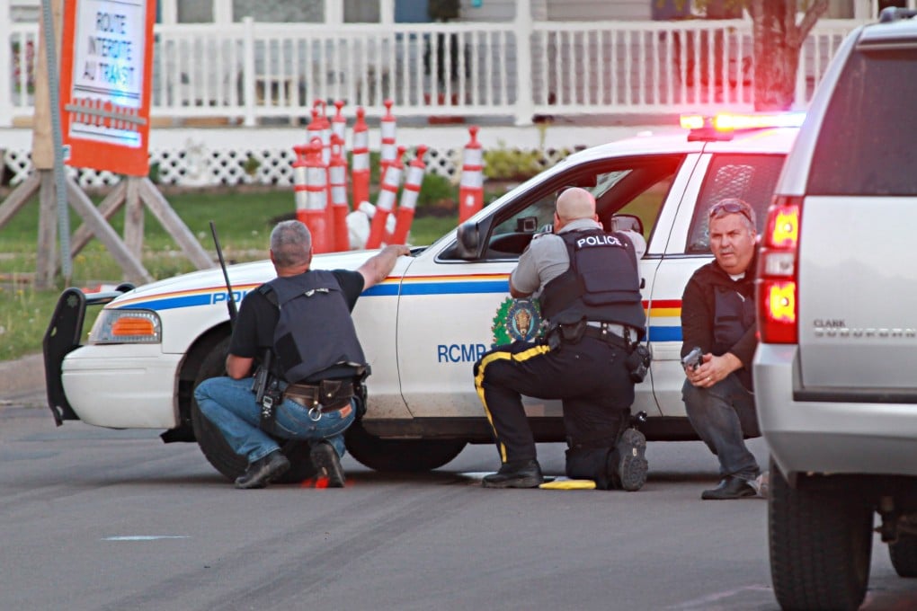 Police officers take cover behind their vehicles in Moncton, New Brunswick, on Wednesday. Photo: AP