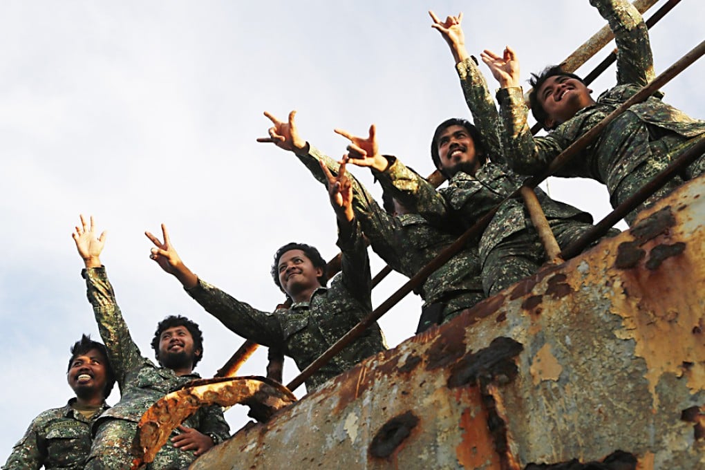 Philippine  Marines wave at local reporters, at the disputed Second Thomas Shoal, part of the Spratly Islands, in the South China Sea. Photo: Reuters