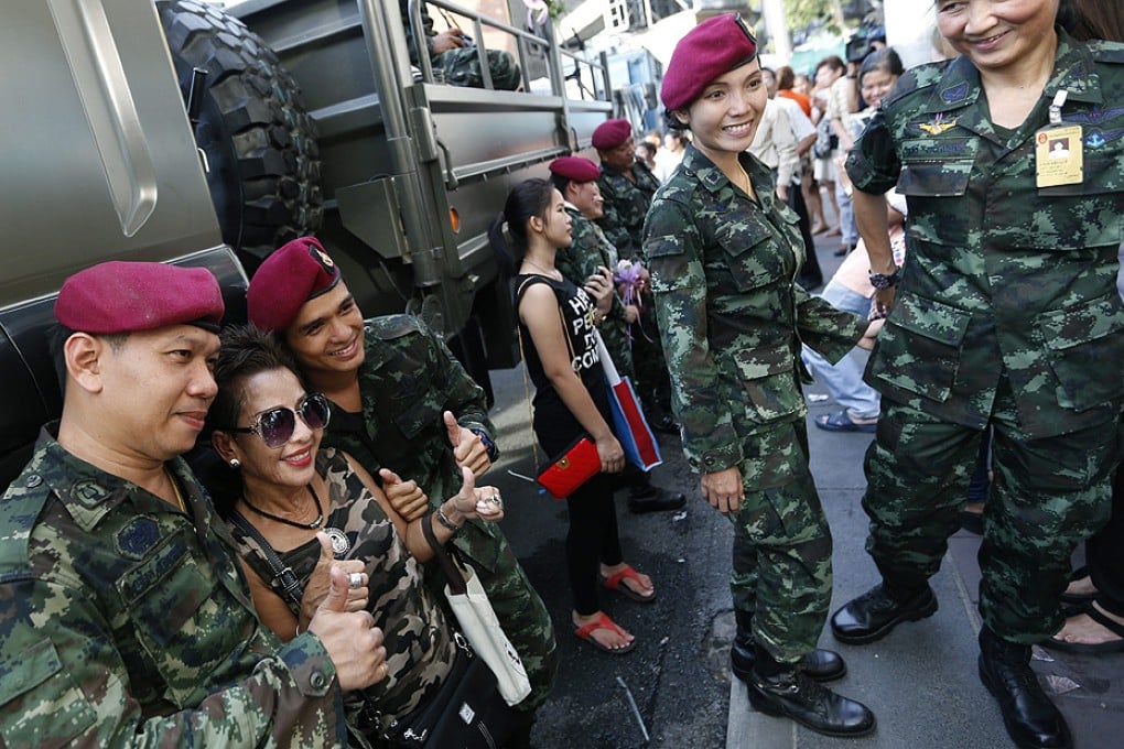 A Thai civilian poses with soldiers during the 'Returning happiness to the people' event near the Victory Monument in Bangkok on Wednesday. Photo: EPA