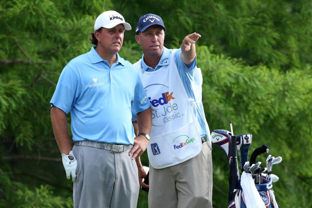 Phil Mickelson talks about a shot with caddie Jim MacKay. Photo: AFP