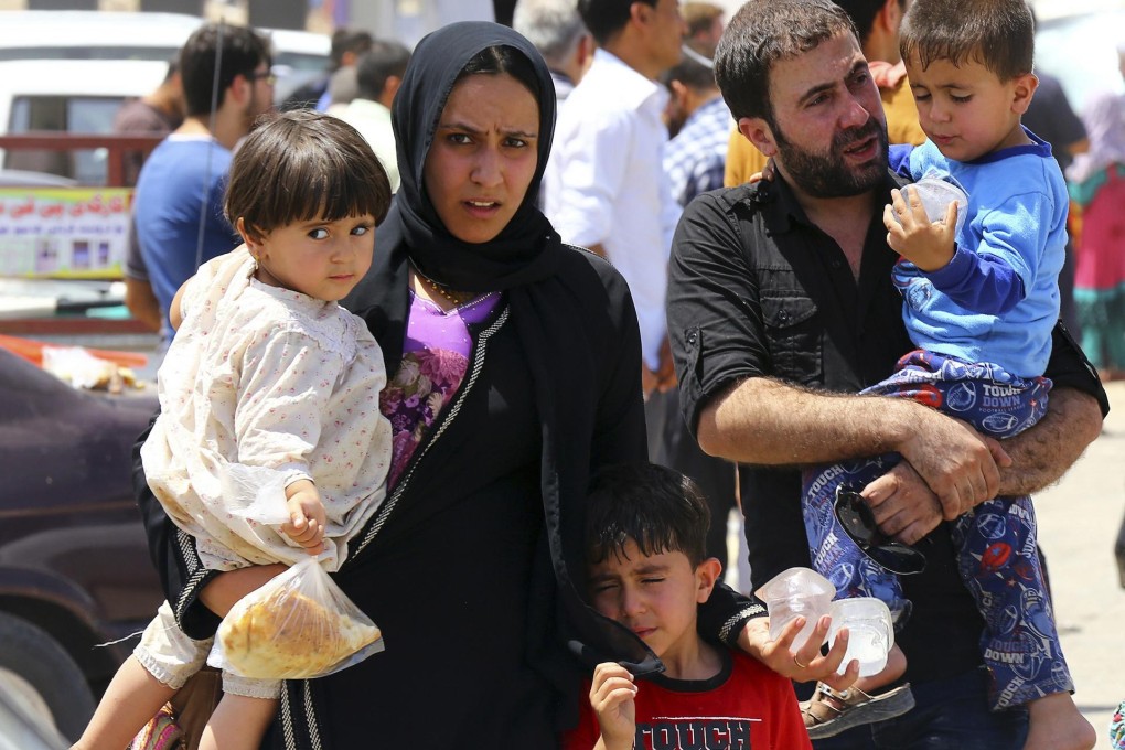 A family fleeing the violence in the northern city of Mosul wait at a checkpoint outside Arbil, in Iraq's Kurdistan region. Photos: Reuters