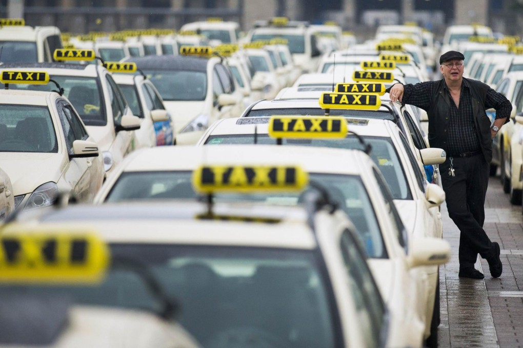 A taxi driver listens to speeches by his colleagues , in front of the Olympic stadium in Berlin during a strike yesterday. Photo: Reuters