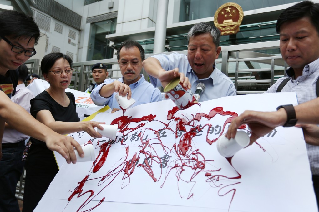 (From 2nd left) Lawmakers Cyd Ho Sau-lan, Fernando Cheung Chiu-hung, Lee Cheuk-yan and other activists splash red oil paint to fake state Council's white paper on "One Country, Two Systems" policy outside the Central Government's Liaison Office in protest.