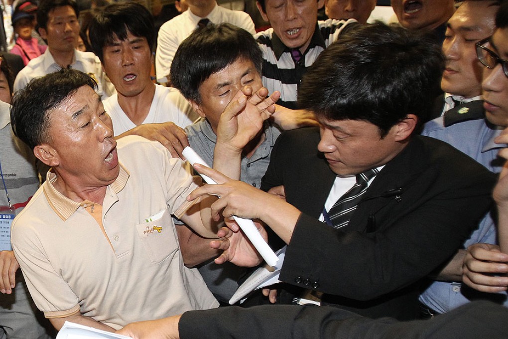 Family members of passengers onboard the sunken ferry Sewol struggle with a security officer at the murder trial of the captain and crew in Gwangju on Wednesday. Photo: AFP