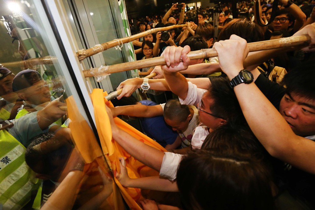 Protesters attempt to lever open the heavily guarded gates at the Legco building. Photo: SCMP