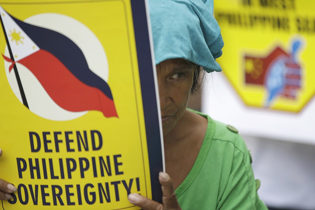 A protester displays a placard during a rally in front of the Chinese Consulate at the financial district of Makati city, east of Manila, Philippines on Friday May 16. photo: AP