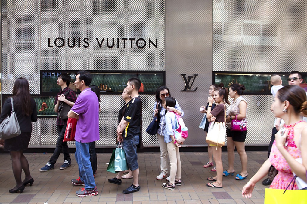 Tourists line up outside a Louis Vuitton store on Canton Road. High-net-worth individuals are shifting away from owning things to seeking experiences. Photo: EPA