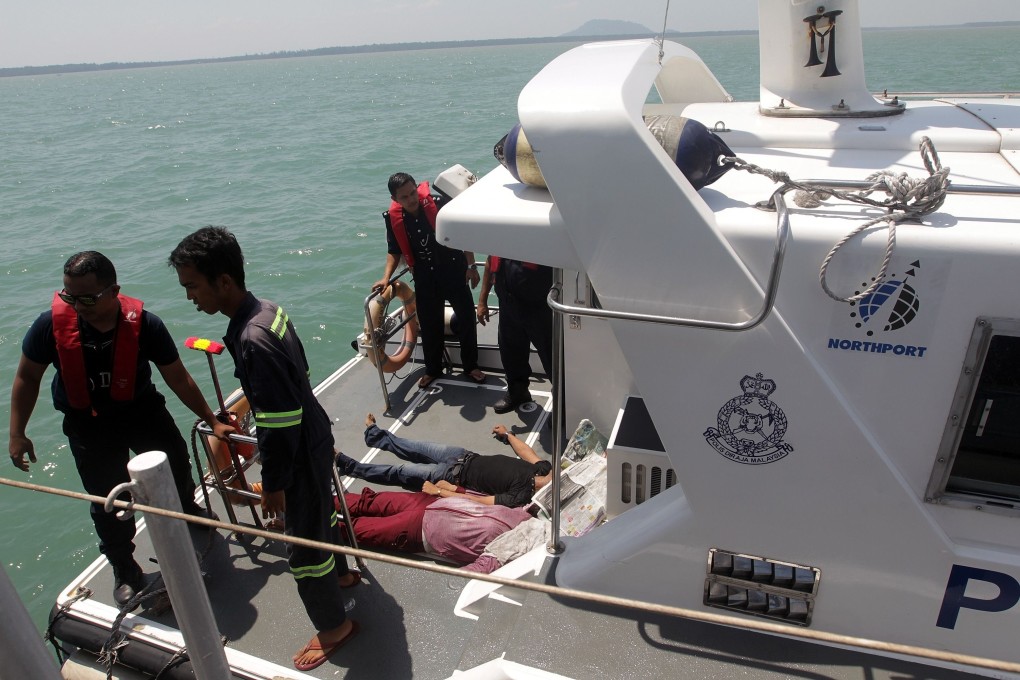 Malaysian marine police officers standing on the deck of a boat with victim's bodies retrieved from the capsized boat. Photo: AFP