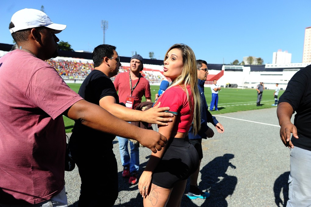 Andressa Urach, a former Miss BumBum pageant contestant is escorted out of the grounds during a Portugal team training session in Campinas, Sao Paulo. Photo: AFP